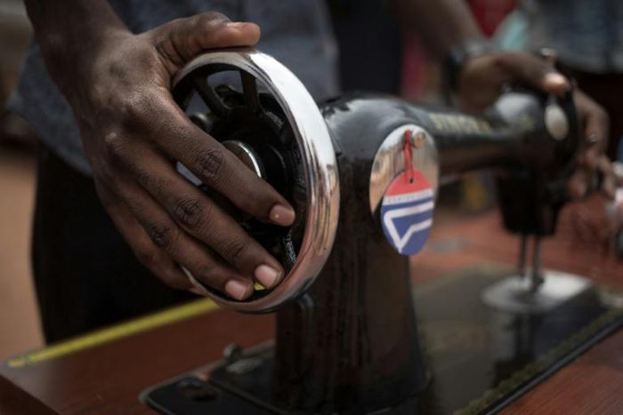 A former child soldier receives a sewing machine to help set up a business after finishing training as a tailor
