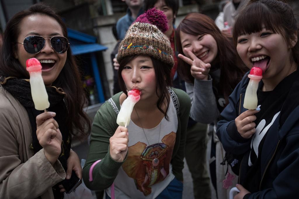 Women pose for a photograph as they munch on phallic-shaped lollipops [Howwe]
