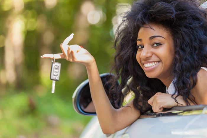 Young lady sitting in a car and holding the car keys