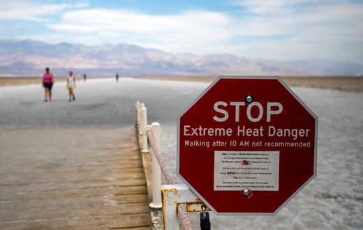 Some photos from over the weekend give context to the danger of visiting Death Valley. This image shows tourists roaming the arid plains behind an "Extreme Heat Danger" sign warning people not to walk through the area after 10 a.m.