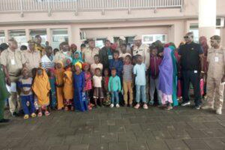 Men of Nigeria Immigration Service, Seme command in a group photograph with the 66 trafficked Nigerians from Ghana in Seme. [NAN]
