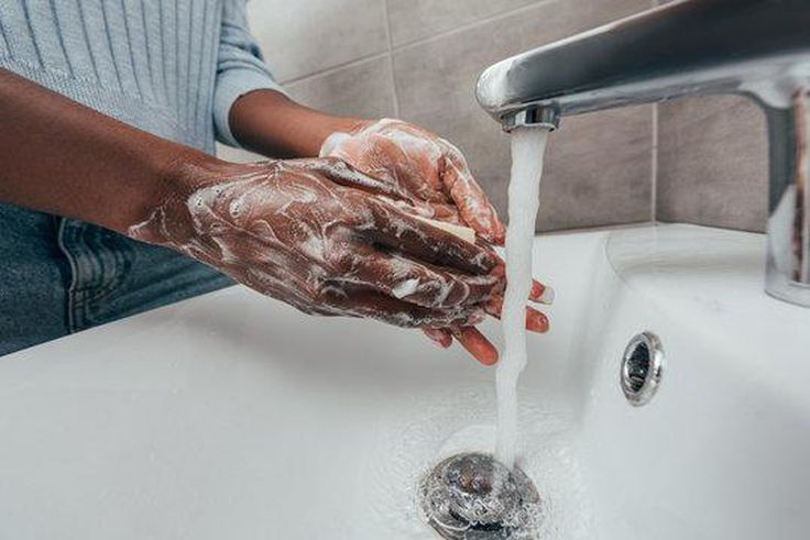 Black person washing hands at the sink [Adobe Stock]