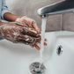 Black person washing hands at the sink [Adobe Stock]