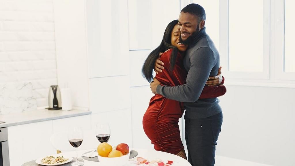 Man and woman hugging and Valentine dinner with wine on table [Image Credit: Gustavo Fring]