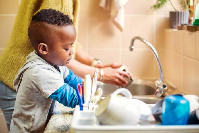 A boy in the kitchen doing the dishes [iStock]