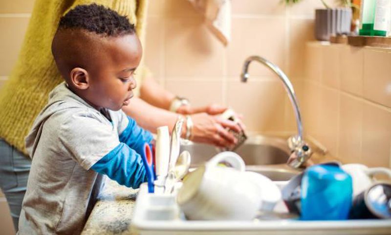 A boy in the kitchen doing the dishes [iStock]