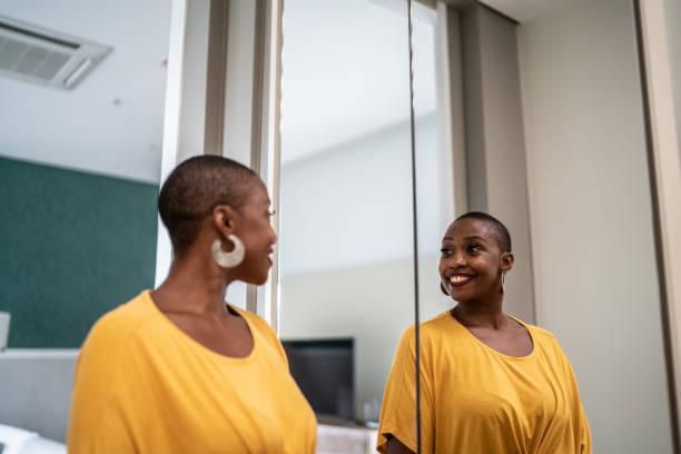 A Black woman looking in the mirror [iStock]