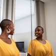 A Black woman looking in the mirror [iStock]