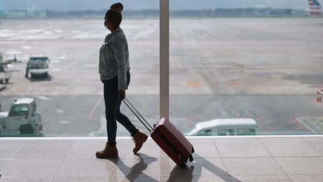 Black woman with suitcase at the airport [iStock]