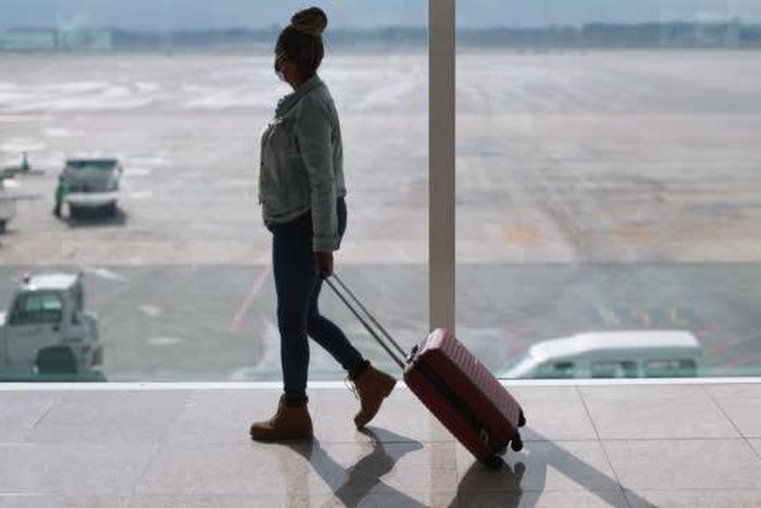 Black woman with suitcase at the airport [iStock]