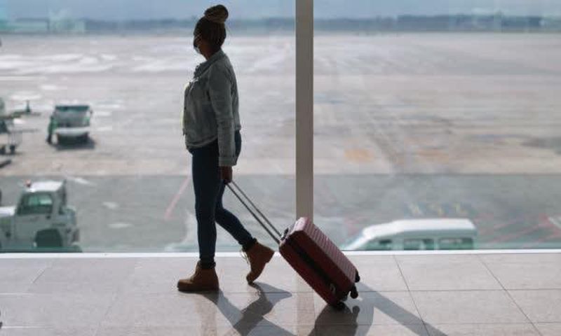 Black woman with suitcase at the airport [iStock]