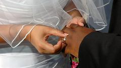 A bride inserting a ring on her grooms finger