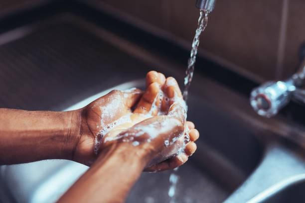 Black person washing hands at the sink [iStock]