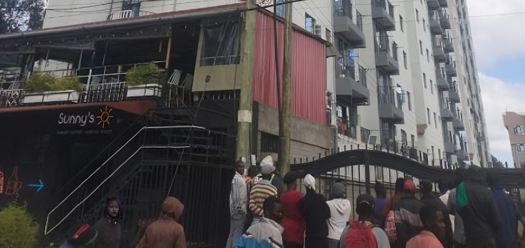 A crowd outside an apartment where a woman was died after reportedly being thrown from one of the houses