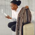 Black woman with suitcase at the airport [Freepik]