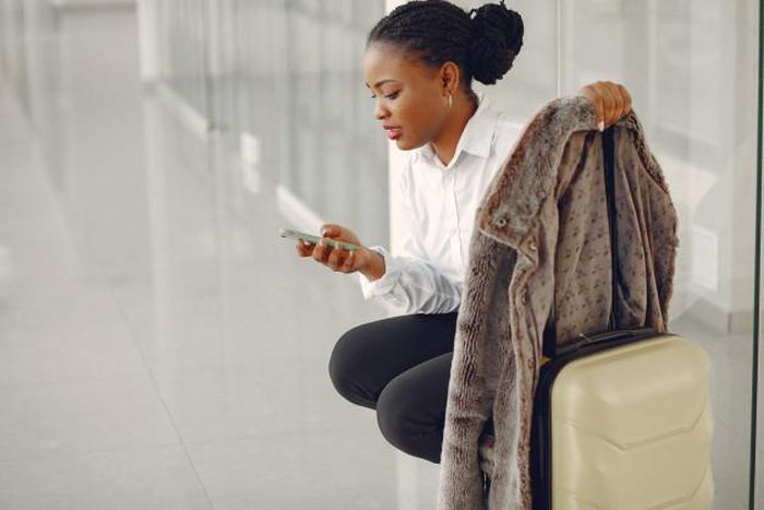 Black woman with suitcase at the airport [Freepik]
