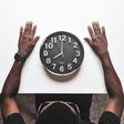 Round black and white analog wall clock in front of a man [Usplash]