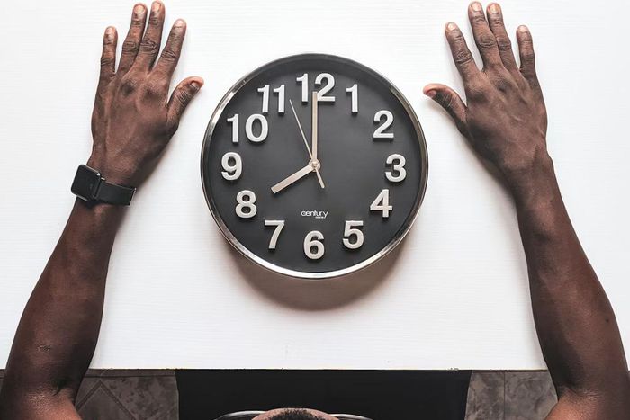 Round black and white analog wall clock in front of a man [Usplash]