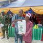 Mr Olusegun Onilude, the Chairman, Badagry Local Government, presenting free food items to Mr Matthew Avoseh, a retired head teacher, during the distribution of free food items to people in Badagry [NAN]
