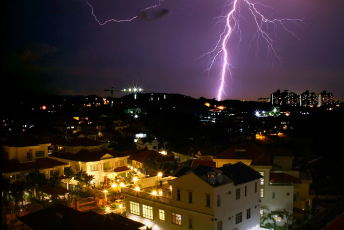 Lightning illuminates the horizon behind a Malaysian cityscape.