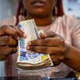 A vendor counts out Nigerian naira banknotes inside a shop at the Ikeja computer village market in Lagos, Nigeria. [Getty Images]