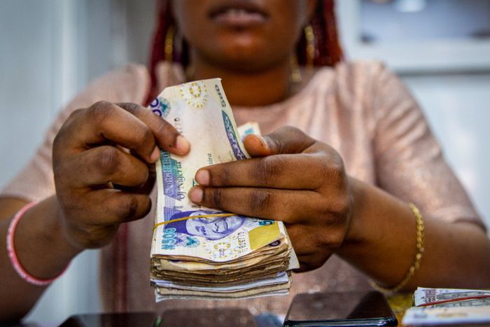 A vendor counts out Nigerian naira banknotes inside a shop at the Ikeja computer village market in Lagos, Nigeria. [Getty Images]