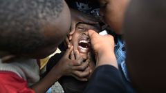 TOPSHOT - A community health worker delivers a polio vaccine to fight against polio virus which is highly contagious and can cause paralysis and lifelong disability, or even death, during the polio immunization campaign in Kiamako, Nairobi on July 19, ...