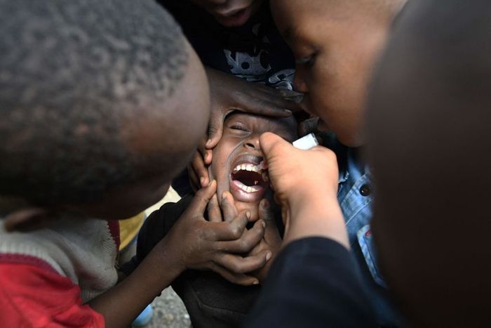 TOPSHOT - A community health worker delivers a polio vaccine to fight against polio virus which is highly contagious and can cause paralysis and lifelong disability, or even death, during the polio immunization campaign in Kiamako, Nairobi on July 19, ...