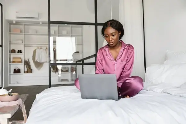 An admission seeker uploading her WAEC result using a laptop in bed
