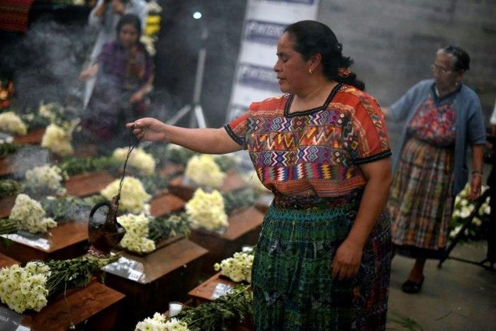 Indigenous women burn incense over urns with the remains of victims from Guatemala's 1960-1996 civil war after they arrived in San Juan Comalapa, Chimaltenango department, west of Guatemala City