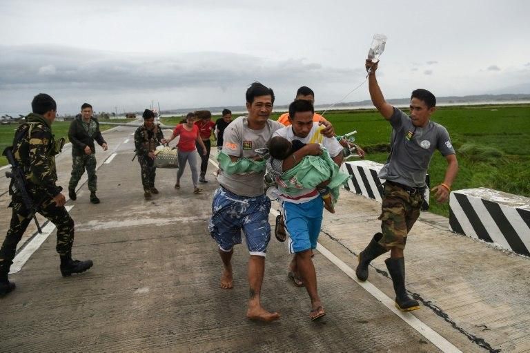 Philippine soldiers help a family with a sick child to a government vehicle after their ambulance failed to make it through fallen debris from Super Typhoon Mangkhut in Baggao town