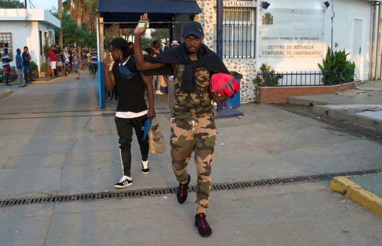 Sub-Saharan migrants gesture as they leave the temporary centre for immigrants and asylum seekers in the Spanish enclave of Melilla on September 19 , 2018, departing to Malaga in Spain