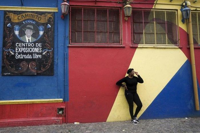 A tourist poses for pictures during a visit to the traditional street museum Caminito in La Boca neighbourhood in Buenos Aires