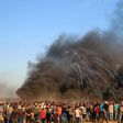 Palestinian protesters watch as tear gas canisters fired by Israeli forces comes through the black smoke of burning tyres during a demonstration on the Israeli border east of Gaza City on September 14, 2018