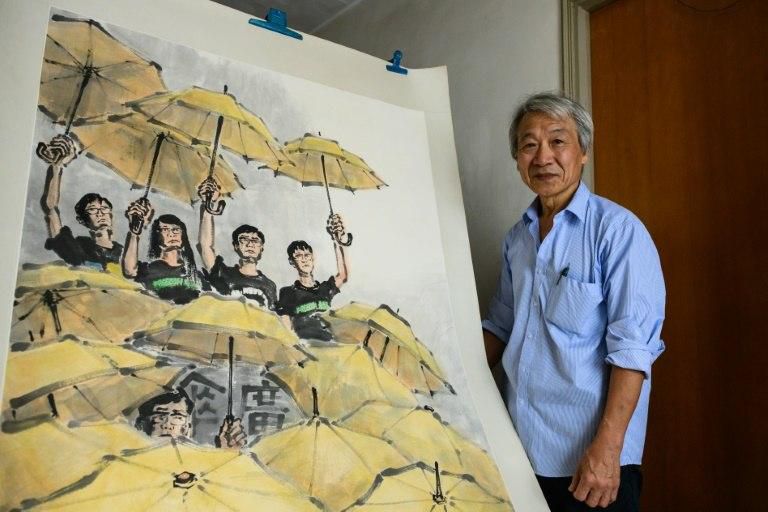 Fong So poses next to an artwork he produced during the 2014 pro-democracy rallies at his studio in Hong Kong