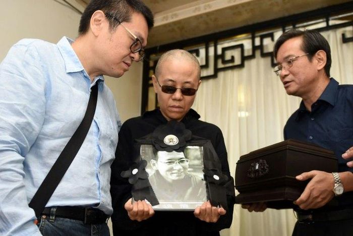 Late Nobel laureate Liu Xiaobo's wife Liu Xia (C) and his brother, Liu Xiaoguang (L), holding a portrait of Liu Xiaobo and receiving the ashes (R) in an urn at a funeral parlour in the Chinese city of Shenyang, Liaoning province
