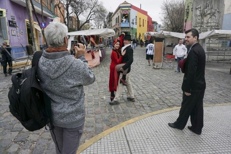 A tourist takes pictures of a couple dancing tango at the traditional street museum Caminito in La Boca neighborhood in Buenos Aires