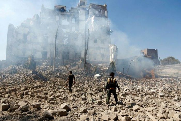 Huthi rebel fighters inspect the damage after a reported air strike by the Saudi-led coalition in Sanaa in December 2017