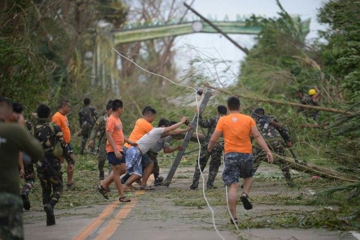 Rescue workers clear a road of debris and toppled electric posts caused by super Typhoon Mangkhut as they try to reach Baggao town