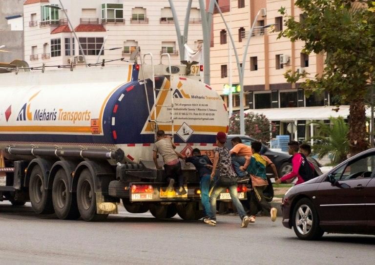 Moroccan migrants try to travel to Europe by jumping on the back of a vehicle at the port city of Nador in Morocco, in hope of finding a better life on September 18, 2018