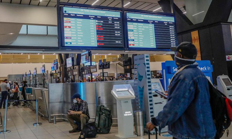 A passenger looks at an electronic flight notice board displaying cancelled flights at Tambo International Airport in Johannesburg on November 27, 2021, after several countries banned flights from South Africa following the discovery of a new coronavir...