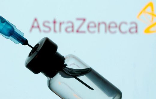 A vial and sryinge are seen in front of a displayed AstraZeneca logo in this illustration taken January 11, 2021.