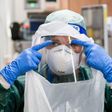 A nurse puts on PPE before treating a coronavirus patient.