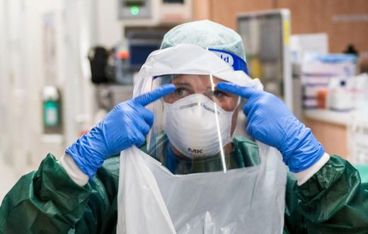 A nurse puts on PPE before treating a coronavirus patient.