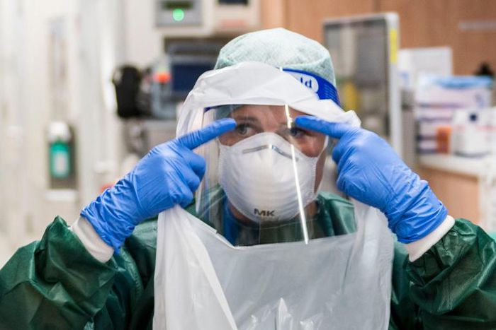 A nurse puts on PPE before treating a coronavirus patient.
