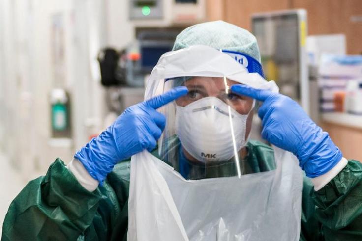 A nurse puts on PPE before treating a coronavirus patient.