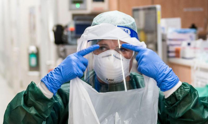 A nurse puts on PPE before treating a coronavirus patient.