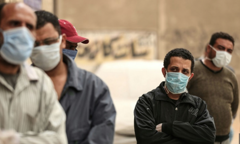 Des hommes égyptiens attendent devant une banque alimentaire, après que des restrictions de mouvement imposées pour lutter contre le coronavirus ont paralysé des moyens de subsistance déjà précaires