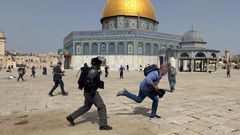 A member of Israeli police runs after a cameraman during clashes with Palestinians at the compound that houses Al-Aqsa Mosque, known to Muslims as Noble Sanctuary and to Jews as Temple Mount, in Jerusalem's Old City, May 10, 2021.