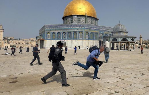 A member of Israeli police runs after a cameraman during clashes with Palestinians at the compound that houses Al-Aqsa Mosque, known to Muslims as Noble Sanctuary and to Jews as Temple Mount, in Jerusalem's Old City, May 10, 2021.